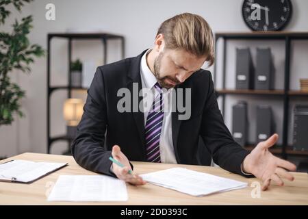 Confused manager checking documents at office Stock Photo