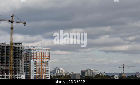 Construction site with silhouette of crane jib with stormy clouds in overcast sky. Concept of real estate development. Urban cityscape aerial view Stock Photo