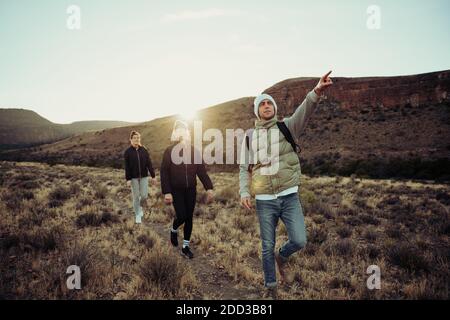 Group of active teens hiking searching for direction pointing in the distance bonding in luscious setting  Stock Photo