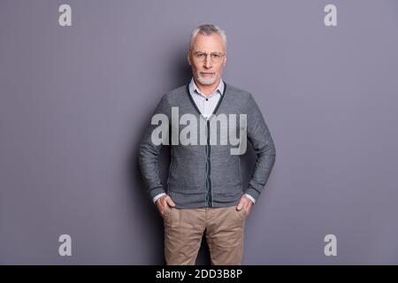 Portrait of his he nice-looking attractive calm content business shark wearing casual formal-wear holding hands in pockets isolated over gray pastel Stock Photo