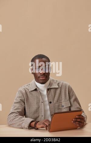 Portrait of African man in eyeglasses looking at camera sitting at the table with digital tablet Stock Photo