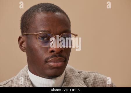 Close-up of African young man in eyeglasses looking at camera against the beige background Stock Photo