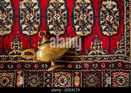 Magic lamp from the story of Aladdin with Genie isolated on red carpet. Stock Photo