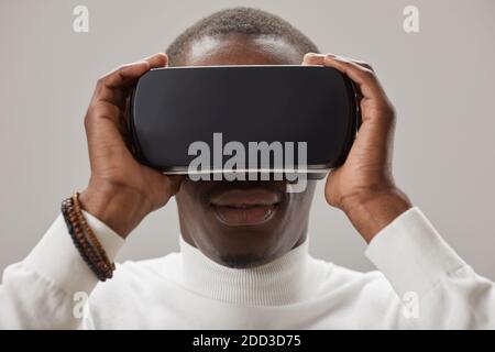 Close-up of African young man wearing 3-D glasses and playing isolated on grey background Stock Photo