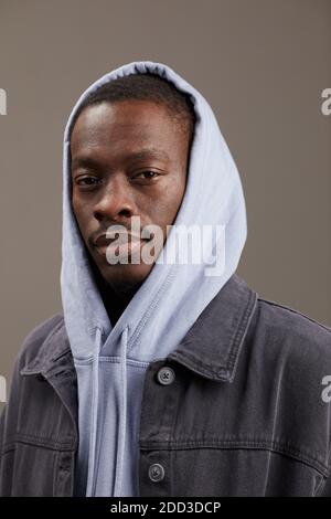 Portrait of African young man in hoody and in jeans jacket looking at camera isolated on grey background Stock Photo