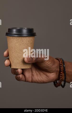 Close-up of man holding disposable cup with coffee in his hand isolated on grey background Stock Photo