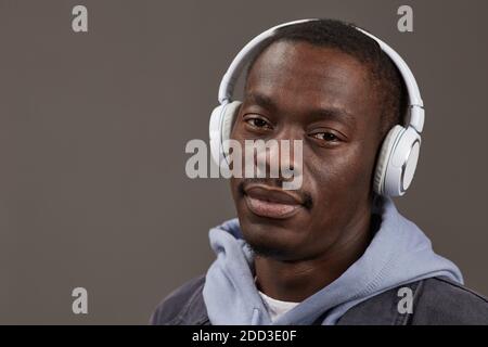 Close-up of African young man in wireless headphones enjoying the music isolated on grey background Stock Photo