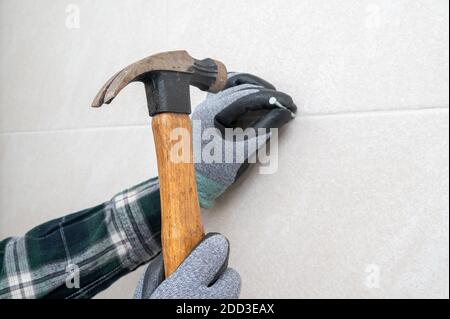 Man's hand holding a hammer and nailing the wall. Stock Photo