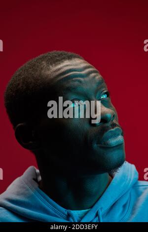 Close-up of African young man looking up with pensive sight isolated on pink background Stock Photo