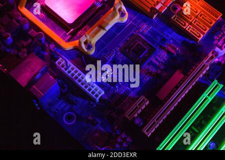 Macro close-up of a microchip, processor, printed circuit Board, or computer motherboard with components: neon colors. The Concept Of Security Of Cybersecurity. Stock Photo