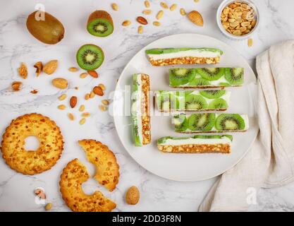 Homemade ricotta and kiwi Cheesecake. Delicious shortbread cake with nuts (almonds and peanuts) on a marble background. Healthy and delicious Breakfas Stock Photo