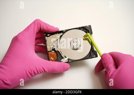 Safely clear and validate your electronic data on the media. Concept. Hands in pink gloves are cleaning the HDD Stock Photo