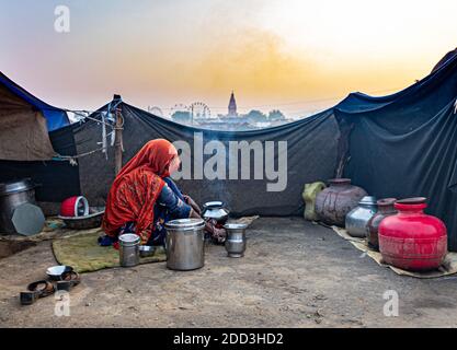 unidentified woman making food in open kitchen,pots and pan on the natural fire for cooking. Stock Photo