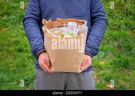 Paper and cardboard prepared for recycling. Bundles of cardboard to be recycled. Man holds a package of paper and cardboard in his hand for recycling. Stock Photo