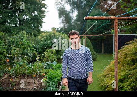 Down syndrome adult man walking outdoors in vegetable garden. Stock Photo