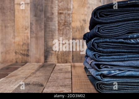 Stack of blue jeans on old wood background with copy space Stock Photo