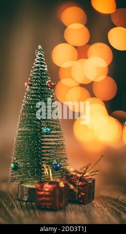 Miniature christmas tree decoration with miniature presents gifts tree decors with sparkling blurred christmas lights waiting for christmas cozy mood Stock Photo