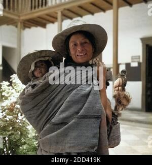 Eine Mutter trägt ihr Kind huckepack durch die Straßen von Cajamarca, Peru 1960er Jahre. A mother carrying her child on her back through the streets of Cajamarca, Peru 1960s. Stock Photo