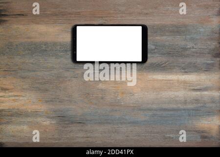Mobile smartphone with blank screen on wood desk background with copy space. Top down Stock Photo