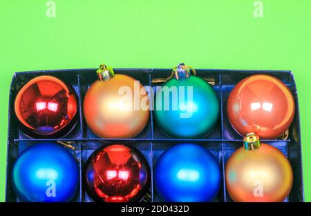 Box of multicolor Christmas balls on green background Stock Photo