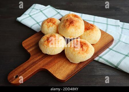 Homemade Heap of Pao de Queijo or Brazilian Cheese Breads on Wooden Breadboard Stock Photo
