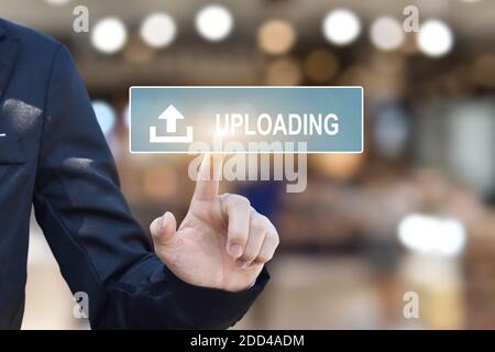 Businessman hand pressing upload button on virtual touchscreen interface, With copy space. Stock Photo