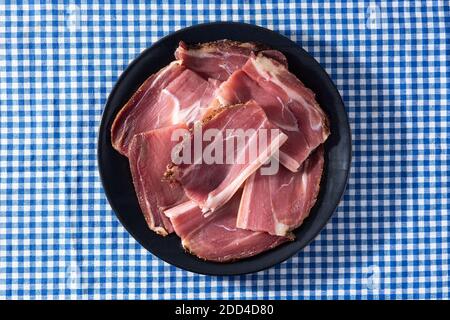 Dried and smoked meat on blue checkered tablecloth Stock Photo