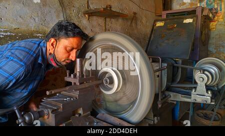 November 2020- Mahroli, Jaipur, India / Professional Indian Mechanic working on lathe machine to repair Bike Tyre. Stock Photo