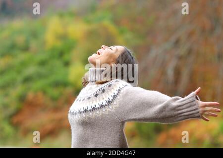 Profile of a middle age excited woman celebrating outstretching arms in the mountain in autumn season Stock Photo