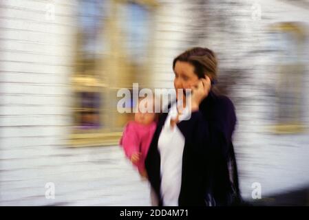 Stressed mother working attending a phone call and taking care of her baby Stock Photo