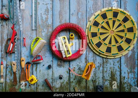 Various tools and supplies hanging on shabby wooden wall Stock Photo