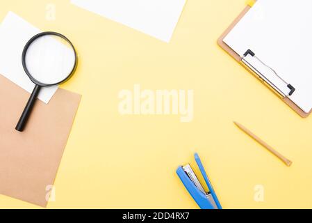 Business composition, layout with blank paper, pen, magnifier on yellow background, top view, space for text Stock Photo