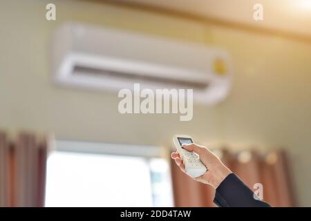 Close up of businessman hand holding remote control directed adjusting of air conditioner. Selective focus Stock Photo