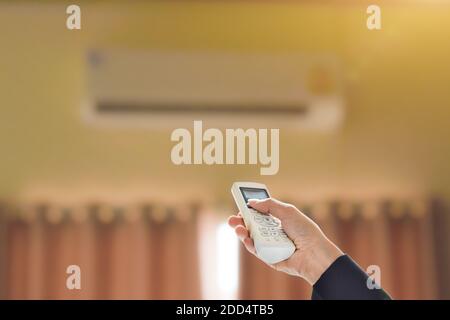 Close up of businessman hand holding remote control directed adjusting of air conditioner. Selective focus Stock Photo