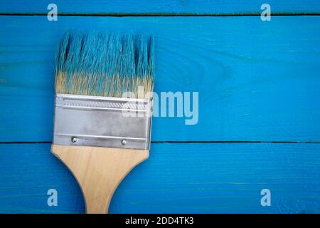 Background for painting works with paintbrush in blue paint lying on the wooden boards that are not completely painted. View from above. Copy space. Stock Photo
