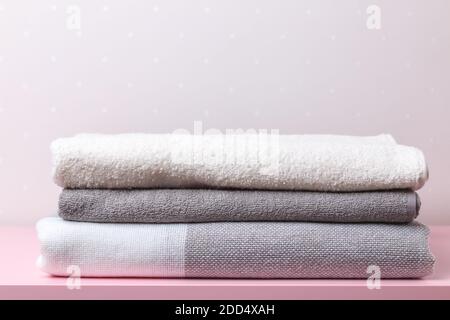 A stack of textiles - blankets and towels on a table against the background of a light wall. Stock Photo