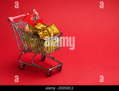 gifts and christmas toys in a trolley on a red background Stock Photo