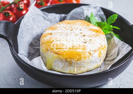 Baked Camembert or Brie cheese in a black pan. Stock Photo
