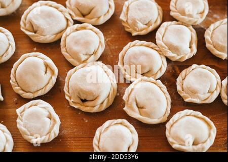 pile of small homemade uncooked dumplings with meat on kitchen table. national traditional Russian cuisine. do it yourself. top view, flat lay Stock Photo