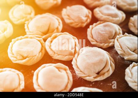 pile of small homemade uncooked dumplings with meat on kitchen table. national traditional Russian cuisine. do it yourself. top view, flat lay Stock Photo