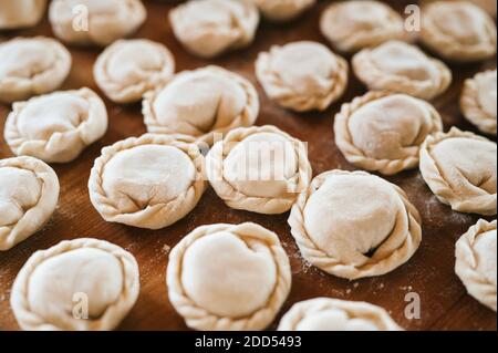 pile of small homemade uncooked dumplings with meat on kitchen table. national traditional Russian cuisine. do it yourself. top view, flet lay Stock Photo