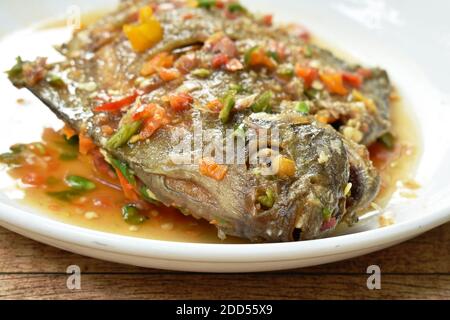 deep fried white pomfret dressing spicy sauce on plate Stock Photo