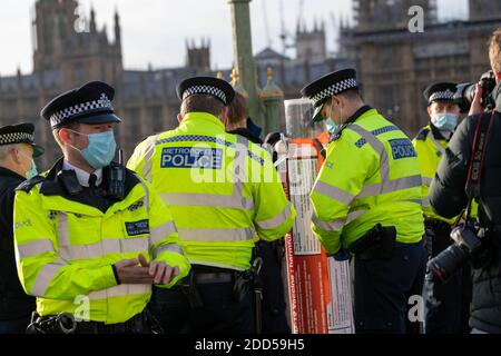 London, UK. 24th Nov, 2020. Piers Corbyn, (brother of former Labour leader Jeremy Corbyn) led a small anti vax anti mask protest and handed out mask exemption cards to passers by and the media. He was accompanied by a man carrying a giant syringe, who was subject to questioning by police on Westminster Bridge. Credit: Ian Davidson/Alamy Live News Stock Photo