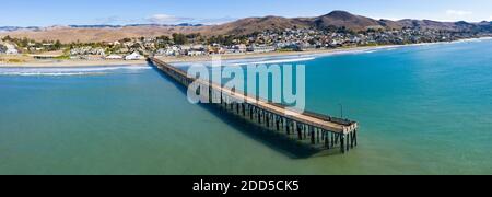 A long pier reaches out into the Pacific Coast in the quaint city of Cayucos, California. This California region is known for its coastal scenery. Stock Photo