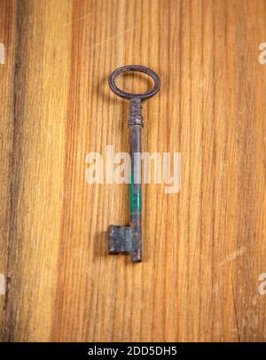 Old Rusted Door Key on natural wood Stock Photo