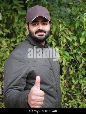 Portrait of a young handsome man showing thumbs up in the forest Stock Photo