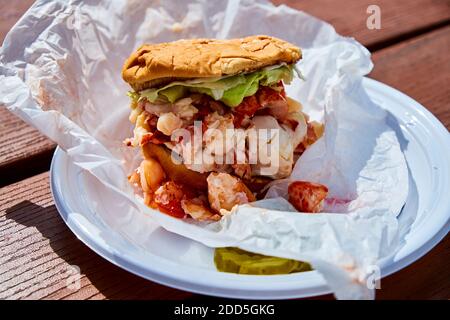 A fresh lobster roll with a hamburger bun and pickle at Young's Lobster Pound in Belfast, Maine. Stock Photo