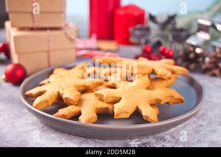 Snowflake shaped homemade Christmas cookies on the plate with Christmas decoration on the background. Stock Photo