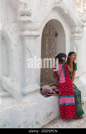 Girl applying thanaka on cheek of lady at Kuthodaw Pagoda, Mandalay, Myanmar (Burma), Asia in February Stock Photo