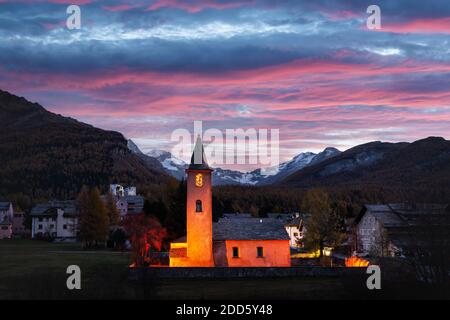 Old christianity church in Sils village (near lake Sils) in Swiss Alps. Red light on building and snowy mountains on background. Switzerland, Maloja region, Upper Engadine. Landscape photography Stock Photo